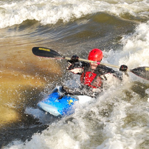 Photo of a man kayaking in a river at a whitewater park