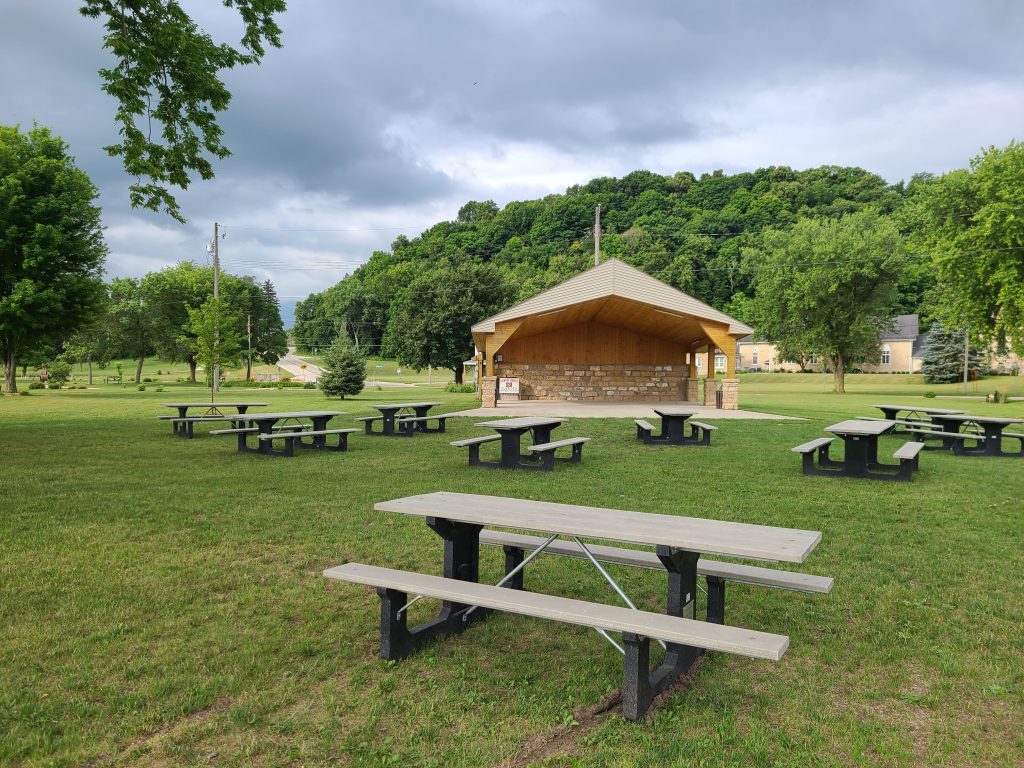 A pavilion with picnic tables nearby in a park.