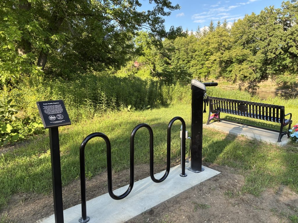 Black bike and kayak rack on concrete at a park with a bike fixit station